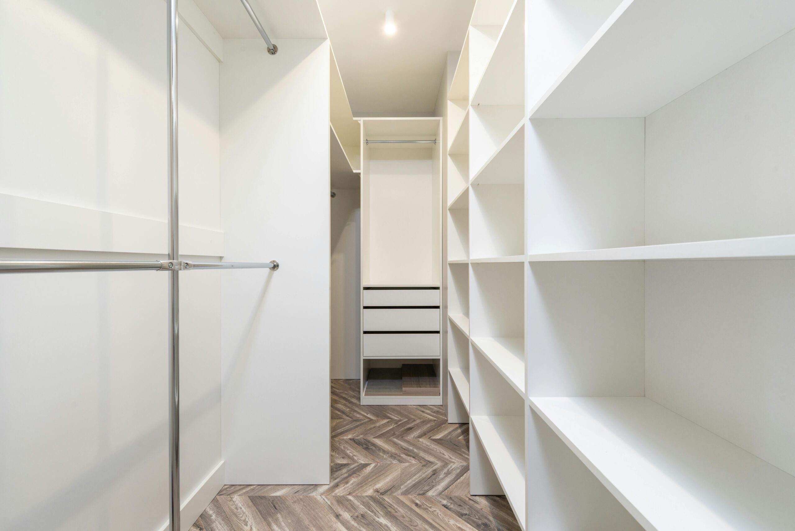 Services Elegant modern walk-in closet with white shelves and storage, offering a clean and organized interior design.